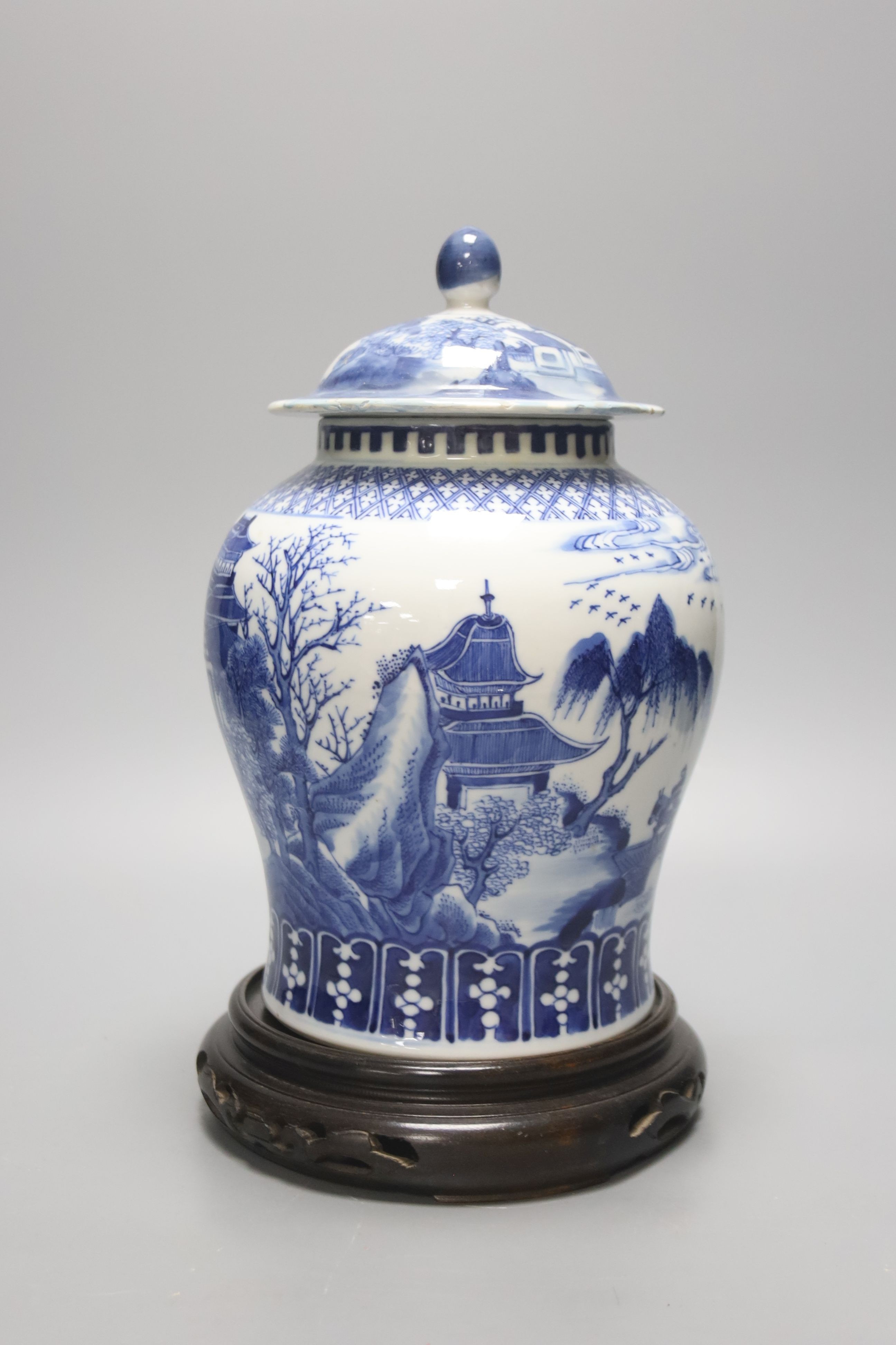 A late 19th / early 20th century Chinese blue and white landscape jar and cover, wood stand 30cm total height